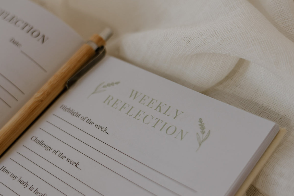Weekly reflection page in the Labour and Love postpartum journal with a bamboo pen