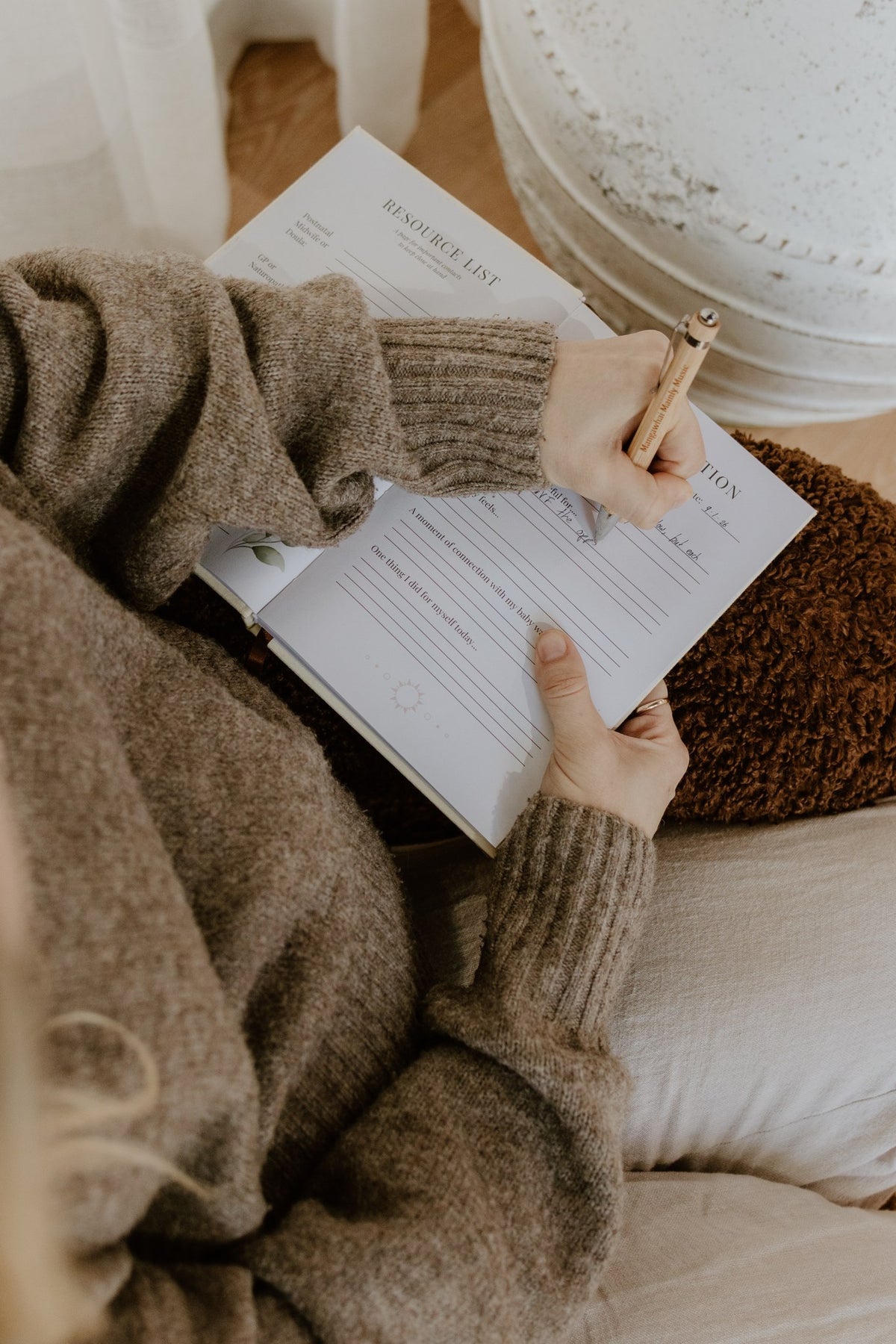 Woman writing in the Labour and Love postpartum journal to reflect on her birth story and recovery