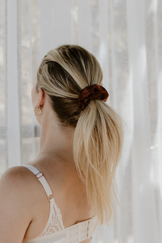 Satin scrunchie holding a woman's ponytail, gentle hair tie for pregnancy and postpartum