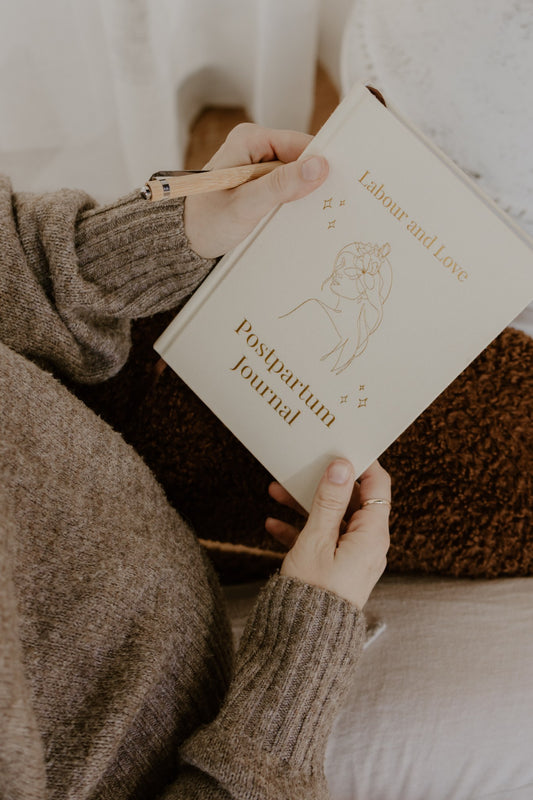 Mother in a cosy knit holding the Labour and Love Postpartum Journal, a guided journal for new mums in NZ