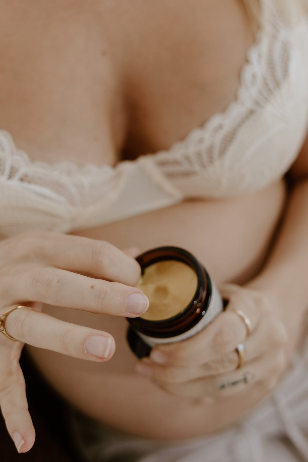 New mum scooping lanolin-free organic nipple butter from the jar to soothe sore breastfeeding nipples