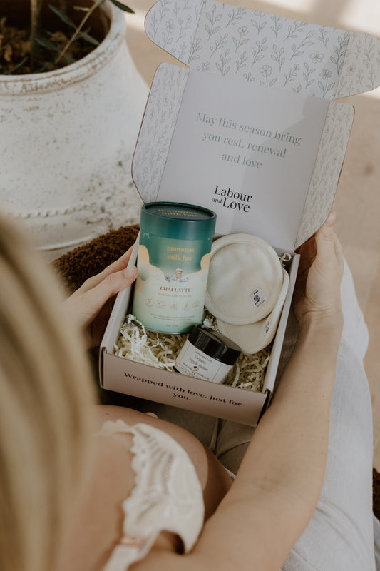 New mum opening the Milk Moon breastfeeding gift box with nipple butter, breast pads and a lactation blend