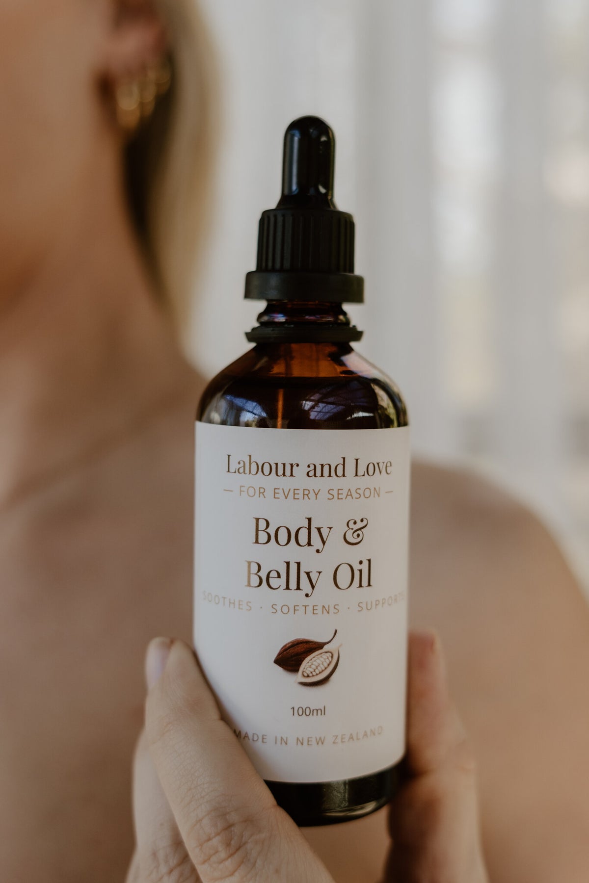 Hand holding a bottle of Labour & Love Sacred Seasons Body & Belly Oil, organic pregnancy and postpartum oil made in NZ