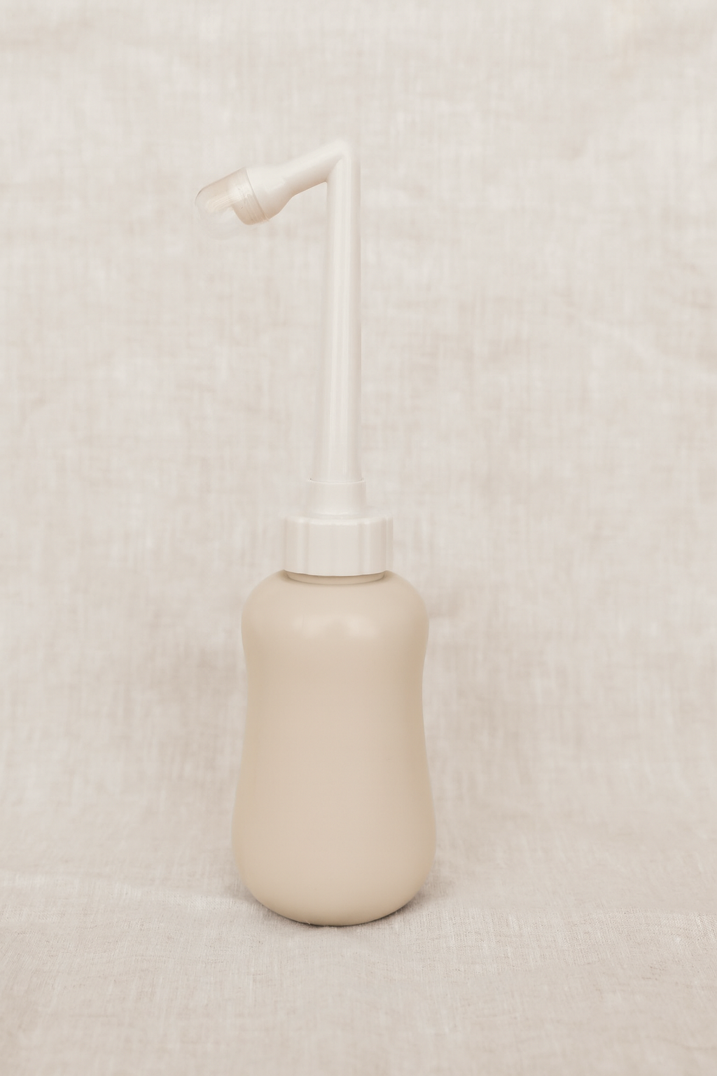 Beige peri bottle with a white pump on a beige textured background