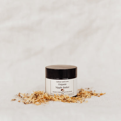 Jar of organic nipple butter on a light grey background with scattered calendula petals
