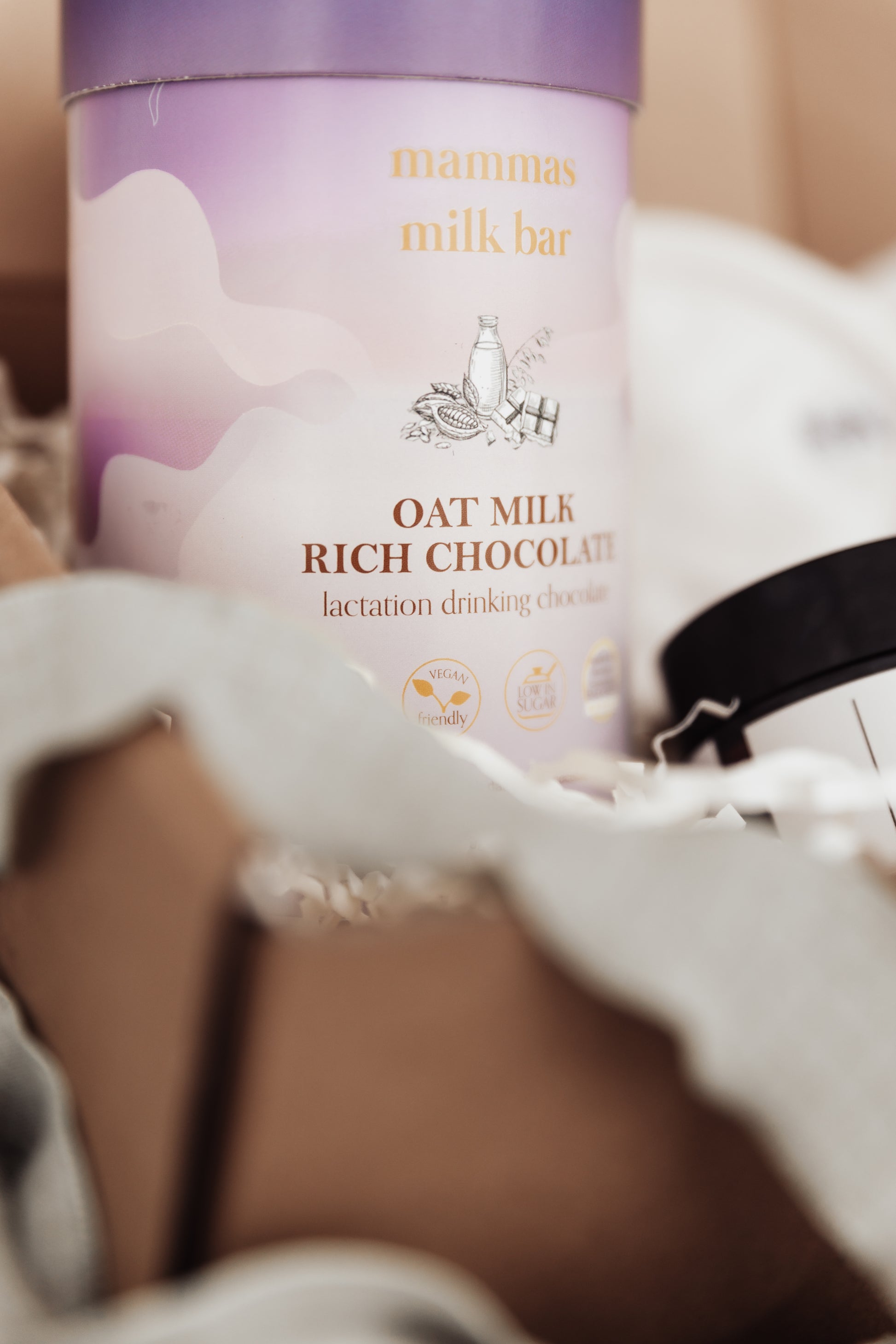 Container of Mamma's Milk Bar Oat Milk Rich Chocolate lactation drinking chocolate on a blurred background.