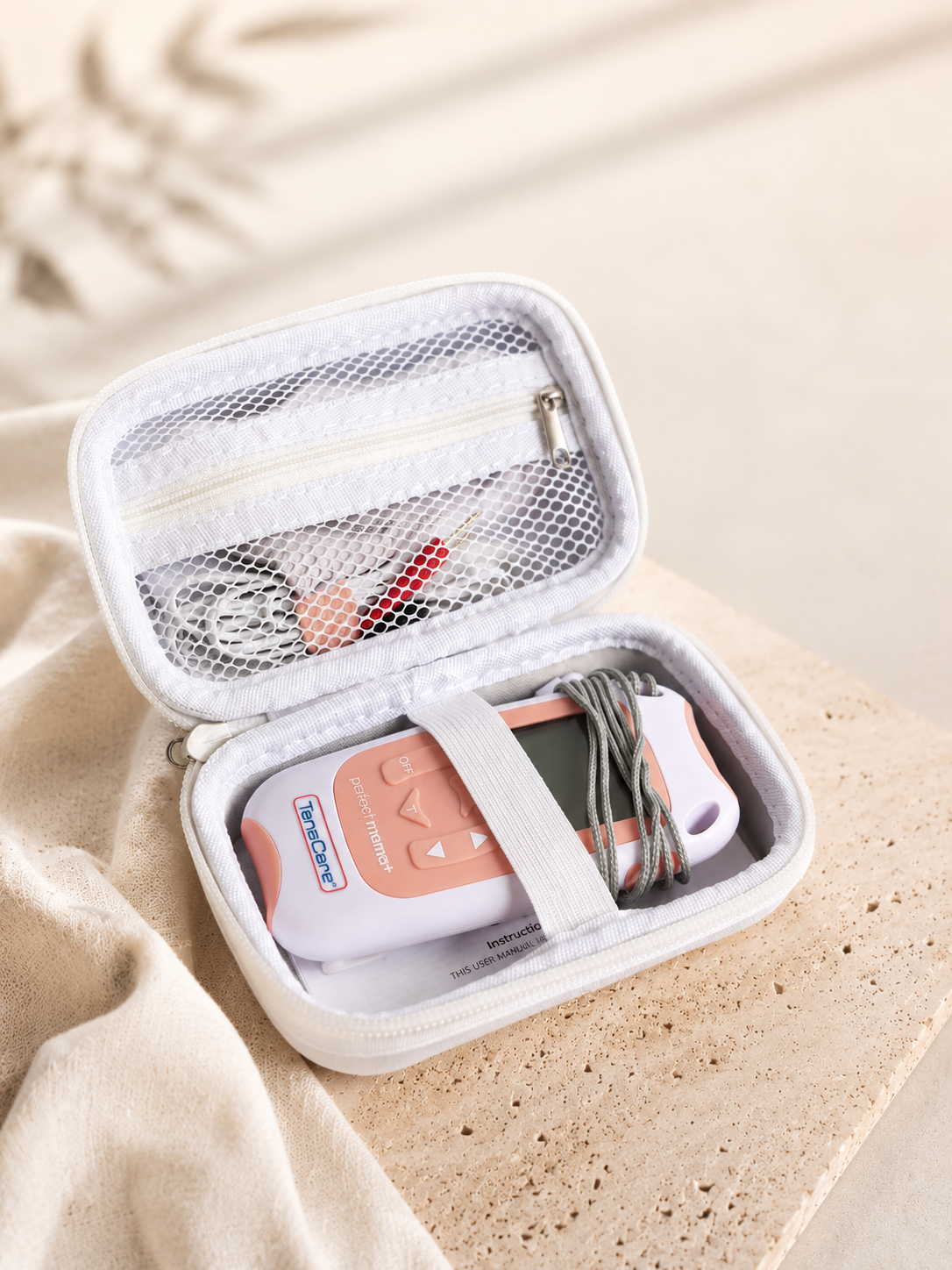 TensCare Perfect mama+ labour TENS machine open in its case on marble, electrode pads and lead wires tucked in — The Surge TENS hire NZ