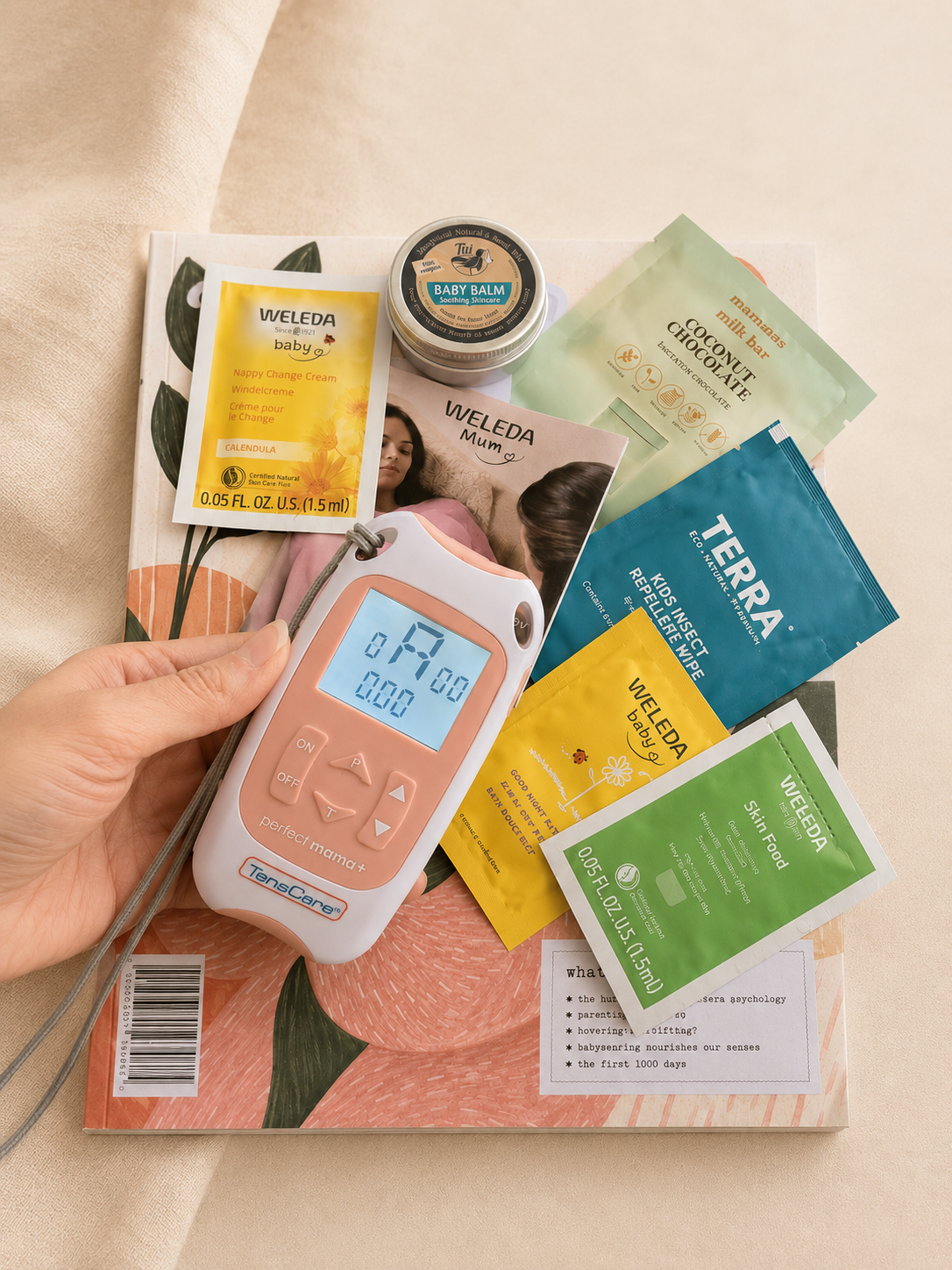 TensCare Perfect mama+ labour TENS machine held with The Nest sample pack behind — TENS hire NZ from Labour and Love
